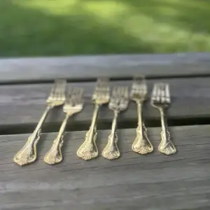 Display of dinner and dessert forks gold color sitting on a wood bench.