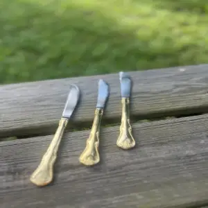 three knives displayed on a wood bench gold color