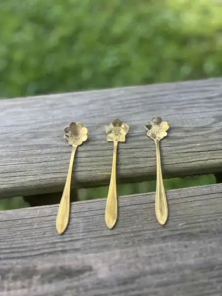 gold teaspoons displayed on a wood bench