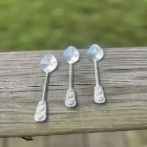 Three silver plated teaspoons sitting on a wood bench