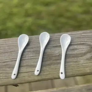 three white porcelain small teaspoons sitting on a wood bench