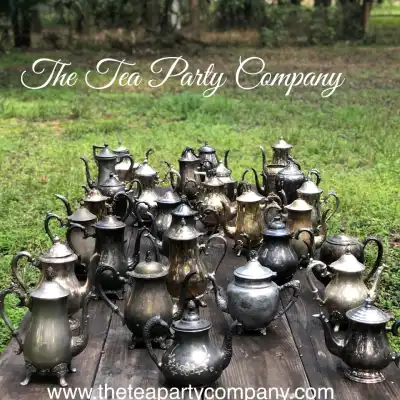 silver plated rentals | The Tea Party Company Wood Table Exibiting Several Silver Plated Tea Pots.