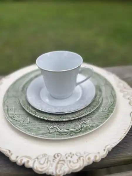 matching-tea-cups-and-saucers | The Tea Party Company white and silver teacup and saucer with a green salad and dinner plate and an off white scrolled charger plate