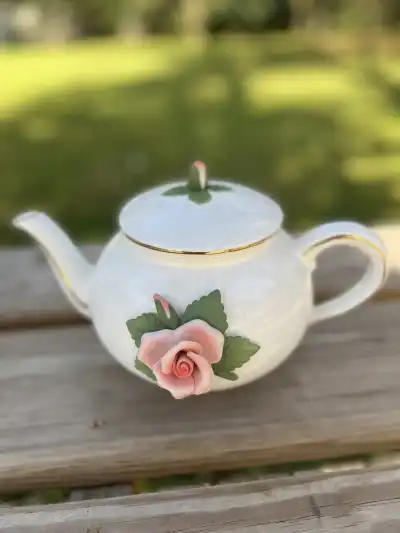 Cute white teapot with a 3d porcelain rose and a tiny red button on the lid>